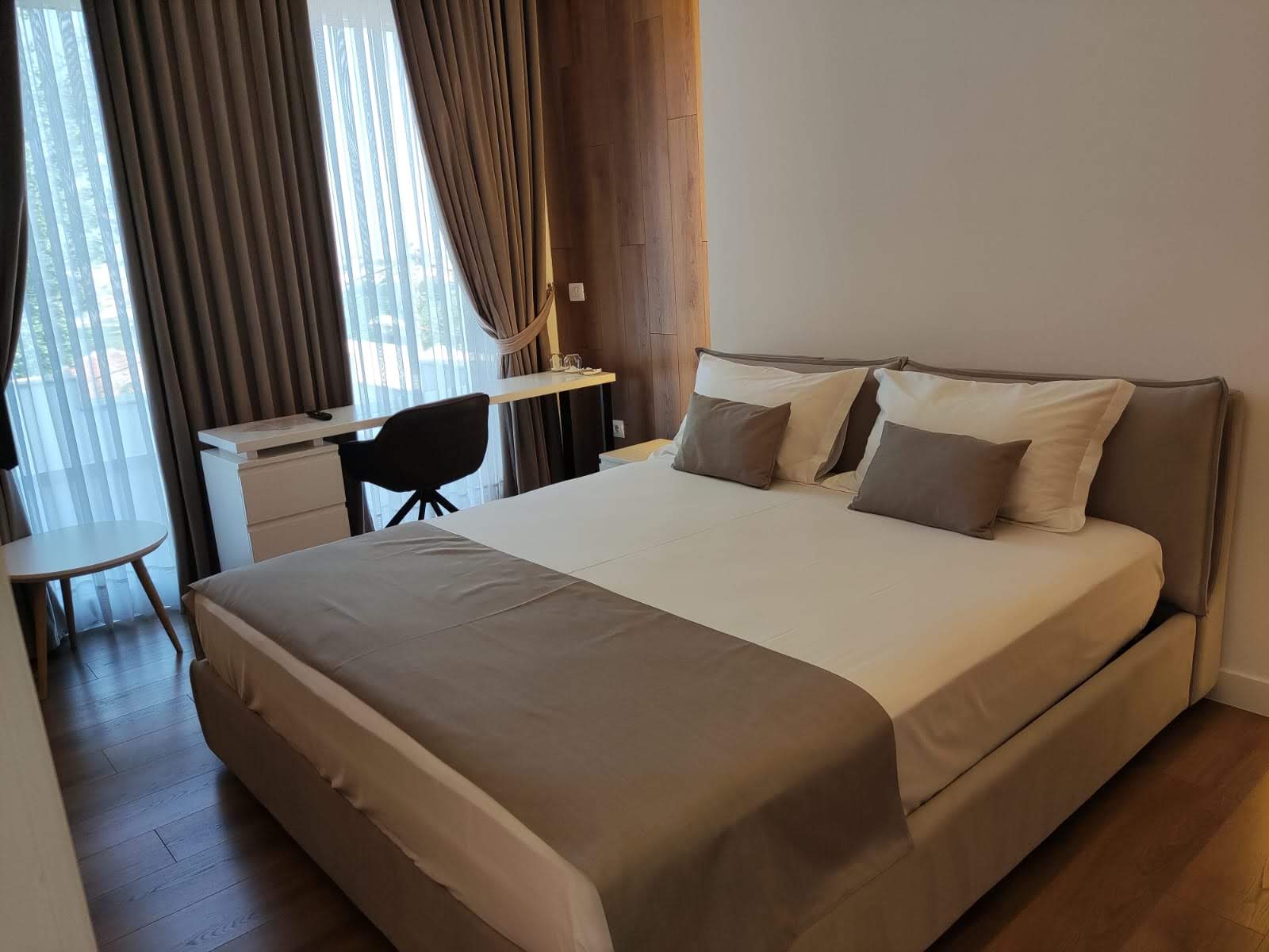 A double bed with an armchair and heavy curtains