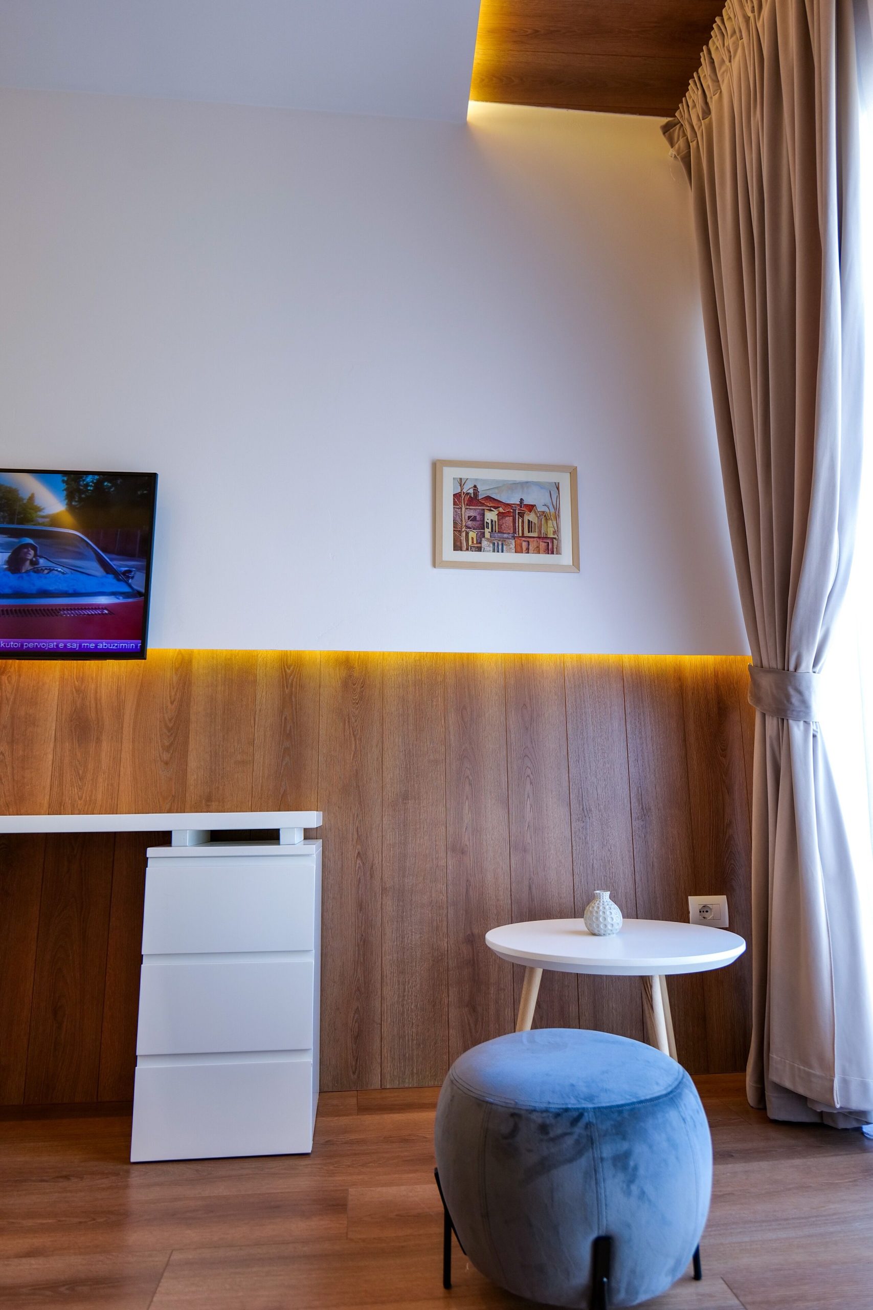 A room with a timber wall, television and blue ottoman
