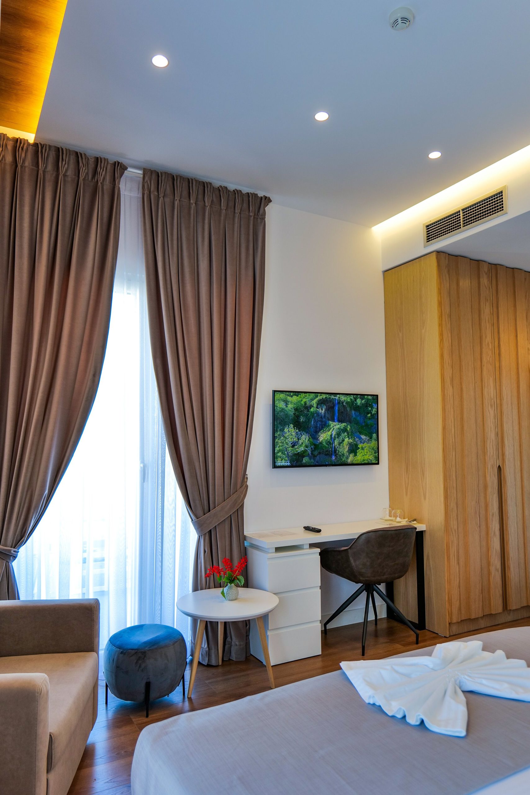 A room with bed, writing desk and wall-mounted television